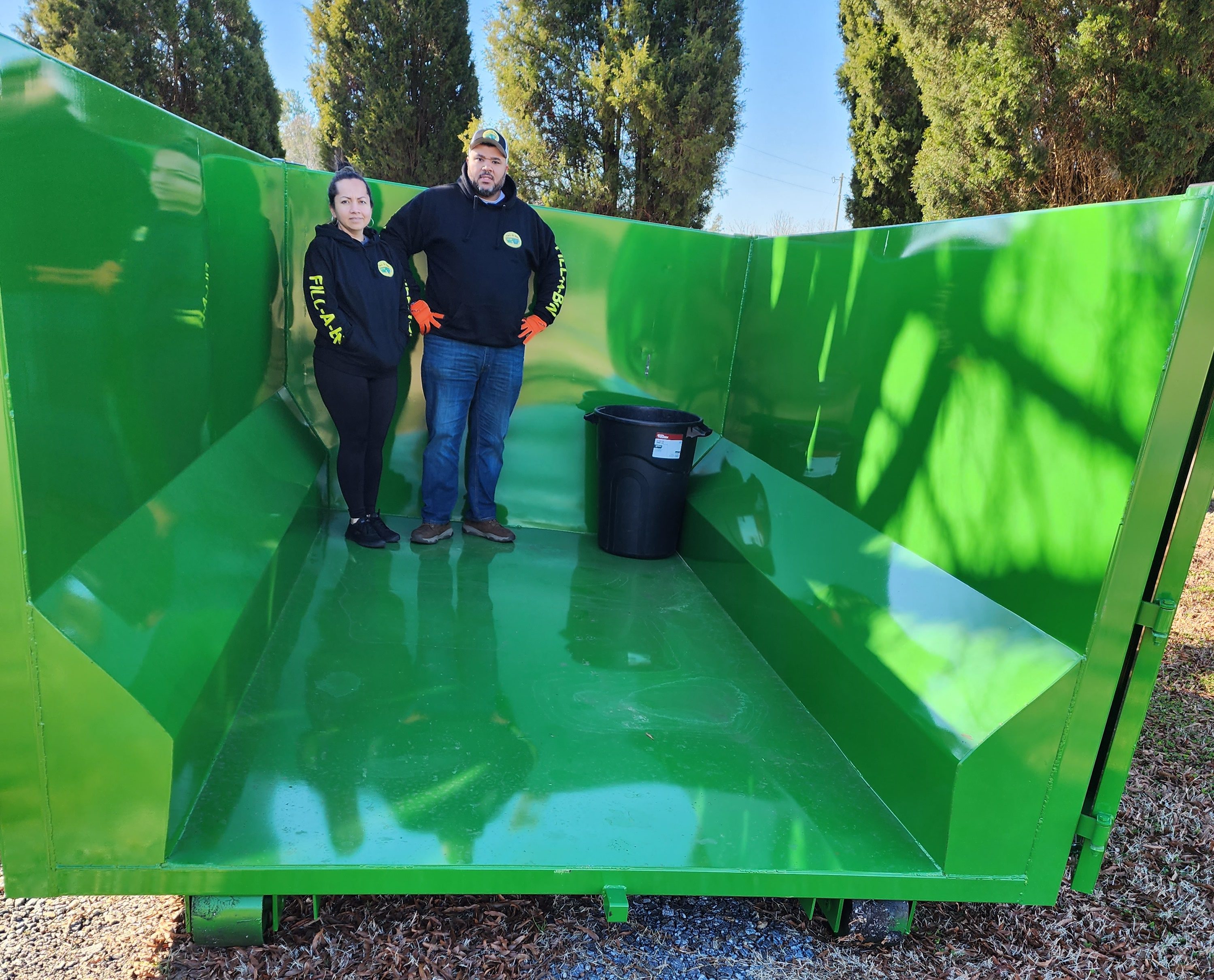 Frank Gibbs and family standing inside of a large empty green dumpster